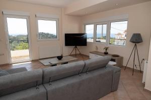 a living room with a couch and a flat screen tv at Aethra Villa in Sounio
