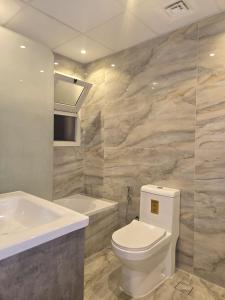 a bathroom with a white toilet and a bath tub at Al Raya Hotel Apartments in Dubai
