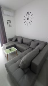 a living room with a couch and a clock on the wall at Golem Horizon apartment in Golem