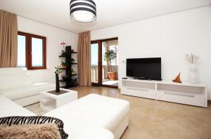 Sala de estar blanca con sofá blanco y TV en Apartments Konavoka, en Cavtat