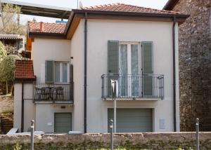 a white house with green shutters and a balcony at CHARMING MOMENT di Villa Porta - Jolie Maison in Luino