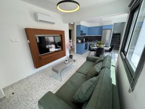 a living room with a green couch and a tv at Luxury Maisonette with Terrace in Paphos
