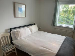a bed with white sheets and a chair in a bedroom at 11 longstone house in Carbis Bay