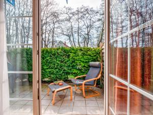 a sliding glass door with a chair and a table at Ostseekoje Prerow in Prerow