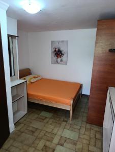 Una pequeña habitación con una cama con una sábana naranja. en Dvokrevetna soba, Spaso, en Petrovac na Moru
