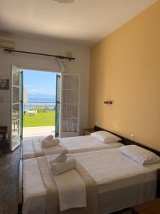 two beds in a room with a view of the ocean at Nikoli Apartments in Benitses
