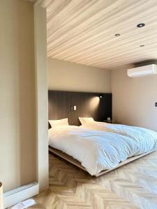 a bedroom with a large bed with a wooden ceiling at 白水温泉竹の倉山荘 in Minami Aso