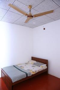 a ceiling fan and a bed in a room at Thulasi Holiday Home in Kilinochchi