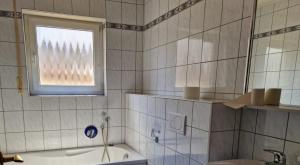 a bathroom with a tub and a window and a sink at Chalet Corallo con camino e ingresso indipendente in Ronco