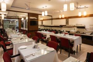 a restaurant with white tables and red chairs at Ahuja Residency Cyber City II in Gurgaon