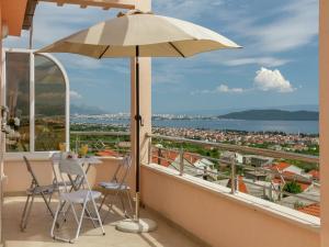 Un balcón con una sombrilla y una mesa y sillas. en Beautiful apartment in between Split and Trogir, en Kaštel Stari