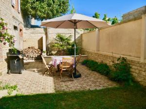 a patio with a table and an umbrella at L'échappée belle in Luc-sur-Mer