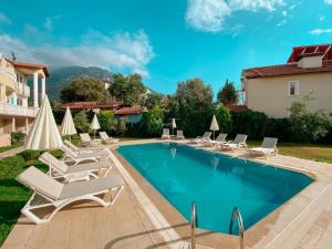 a swimming pool with lounge chairs and a house at Ng Hisar Apart Hotel in Fethiye
