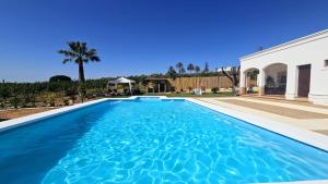 una piscina con agua azul frente a una casa en Casa Rural Limones, en La Puebla de Cazalla