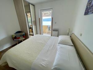 a bedroom with a large white bed and a balcony at Guest House Donatela in Valun