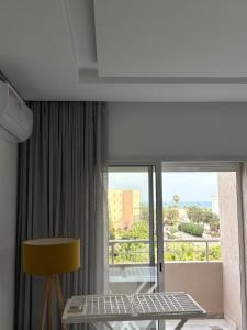 a room with a balcony with a table and a window at Dar GAMRA Luxury apartment with sea view in Hammamet Sud
