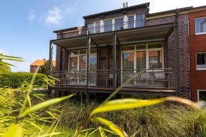 a house with a balcony on the side of it at Wohnung 14 Am Januspark in Juist