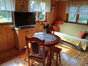 a living room with a table with a television and a bed at Domek letniskowy Iwonka in Zbychowo
