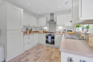 a white kitchen with white cabinets and a sink at Finest Retreats - Cove House in St Austell