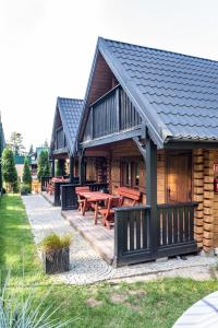 Una cabaña de troncos con mesas de picnic en una terraza. en Domki z bali Deluxe, en Jarosławiec