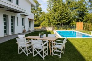 a wooden table and chairs in a yard with a pool at Aristotelia Gi Ikies - Olympiada Poolside Retreats in Olympiada