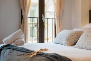 a bed with white sheets and pillows and a window at Ático Cierzo Nuevo Duplex Terraza WiFi 1 BR in Zaragoza