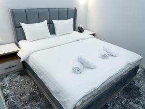 a bed with white sheets and slippers on it at Express Tashkent Hotel&Spa in Tashkent