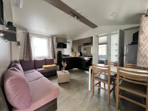 a living room with a purple couch and a table at Mobil-Home VI07 Camping La Carabasse VIAS-PLAGE in Vias