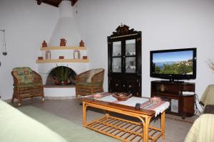 ein Wohnzimmer mit Fernseher, Tisch und Stühlen in der Unterkunft Sunset House in Klíma