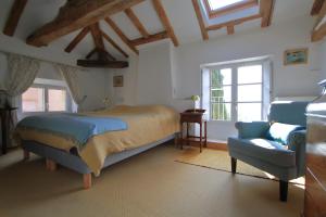 una camera da letto con un letto, una sedia e finestre di Cuq en Terrasses a Cuq-Toulza