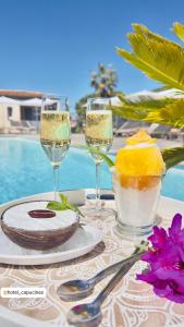 a table with wine glasses and a plate of food at Les Capucines Saint Tropez in Saint-Tropez