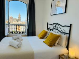 een slaapkamer met een bed met gele kussens en een raam bij Apartamentos Alcazaba in Málaga