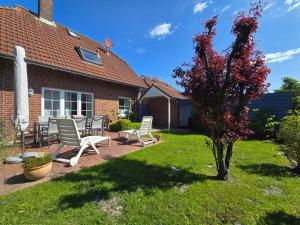 a yard with chairs and a tree with red leaves at Ferienwohnung Ebbe in Dornum