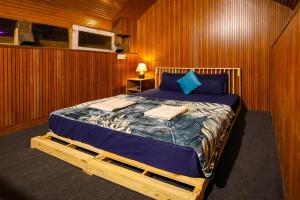 ein Schlafzimmer mit einem Bett in einer Holzwand in der Unterkunft Moksha Woodhouse in Kasol + 30 Fotos