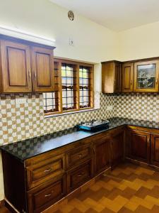 eine Küche mit Holzschränken und einer Arbeitsplatte in der Unterkunft 3BHK Spacious Villa near Rajagiri Hospital in Ernakulam