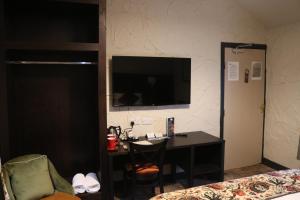 a hotel room with a desk and a television on a wall at Black Dog Inn in Bolton