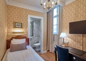 a bedroom with a bed and a desk and a bathroom at Scandic Gamla Stan in Stockholm