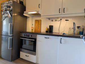 a kitchen with white cabinets and a stainless steel refrigerator at Spacious and cozy studio apartment with balcony in Oslo