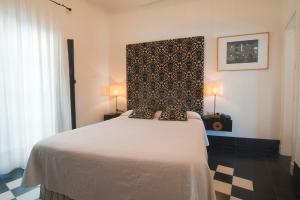 a bedroom with a bed with a black and white patterned headboard at Hostal Casa Alborada in Conil de la Frontera