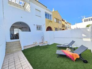 a backyard with a white wall and chairs and grass at ref. 67 casa alexandra in Zahara de los Atunes