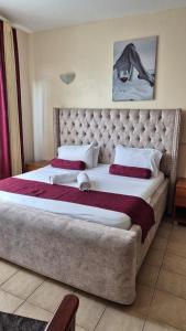 a bedroom with a large bed with a large headboard at Impala Suites in Mombasa