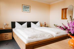 a bedroom with a bed with white sheets and flowers at Pension Jodlbauer in Schöllnach