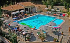 a swimming pool with people sitting in chairs and umbrellas at Elli Marina Studios & Apts Benitses Mare in Benitses