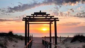 a wooden walkway to the beach with the sunset at Hostal Arcos Beach Chipiona in Chipiona +16 photos