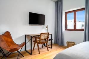 a bedroom with a desk and a tv on a wall at Limehome Porto Rua Das Oliveiras in Porto