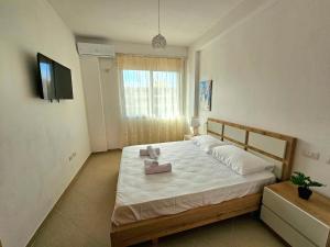 a bedroom with a large bed with a tv on the wall at Vlora Beach Apartment Orikum in Orikum
