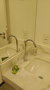 a bathroom sink with two faucets and a mirror at Studio 803 in Marília