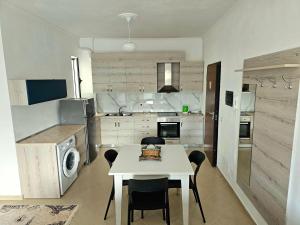 a kitchen with a table and a white table and chairs at Vlora Beach Apartment Orikum in Orikum