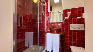 a red tiled bathroom with a shower and a sink at Hostal Casa Alborada in Conil de la Frontera