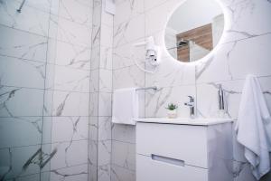 een witte badkamer met een wastafel en een spiegel bij Vila Lena Pool Resort - Apartman 13 in Vrdnik +16 foto's